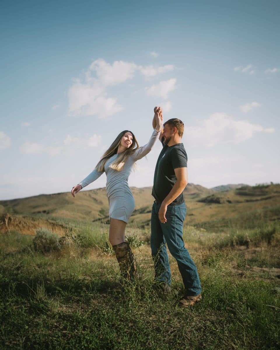 Couple dancing together on a grassy hilltop