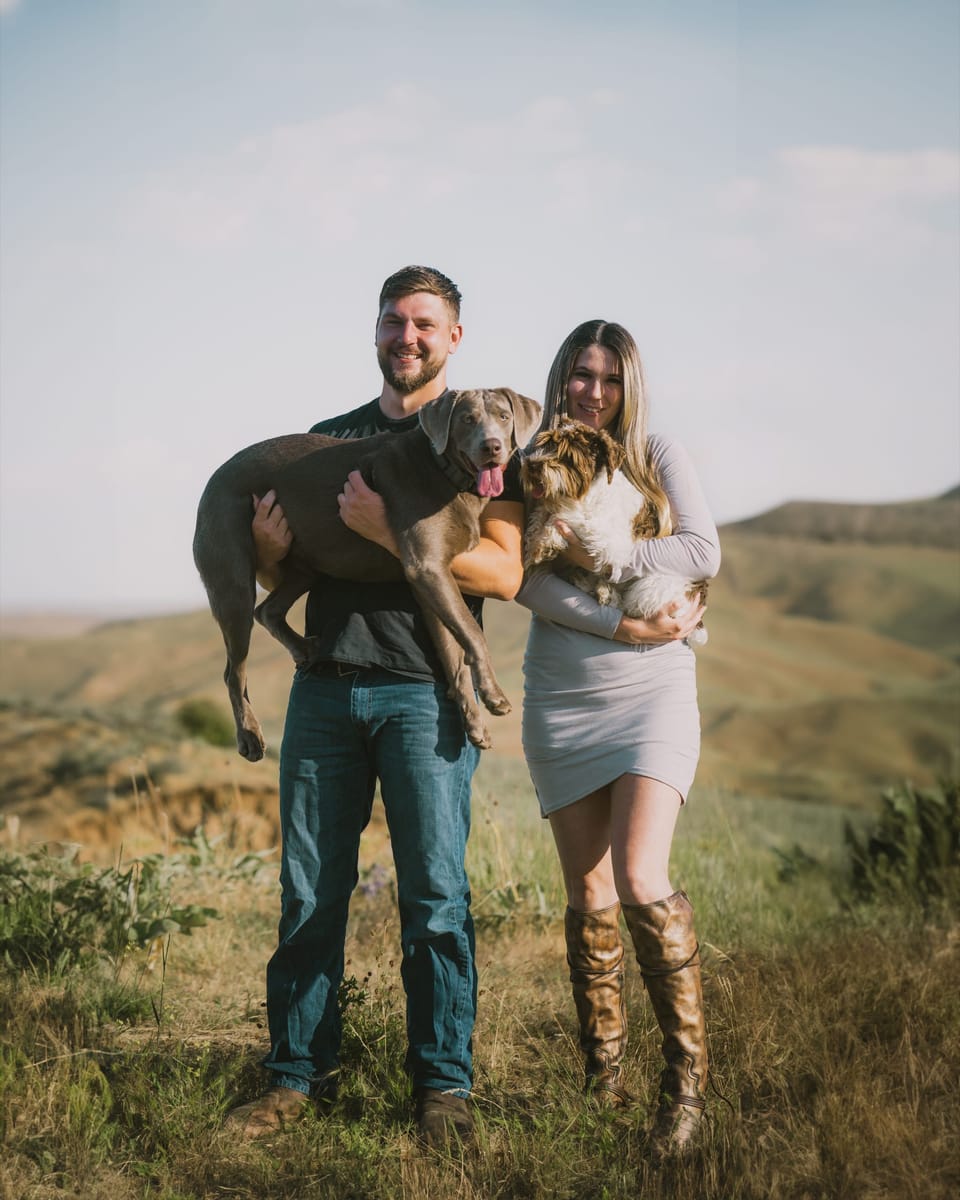 Couple holding their dog in a grassy field