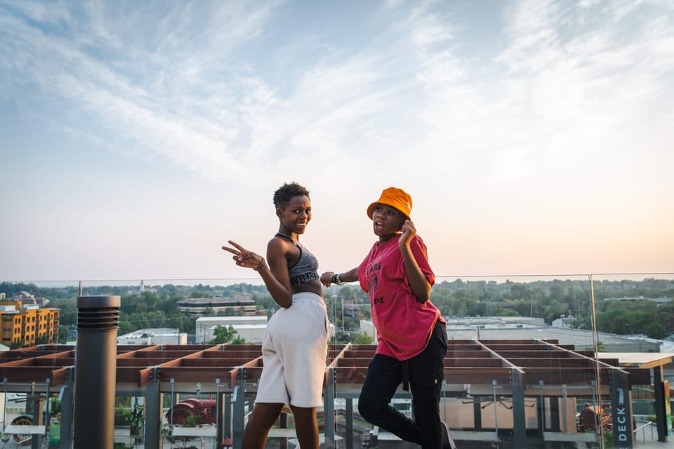 Two friends laughing together on a city rooftop at sunset