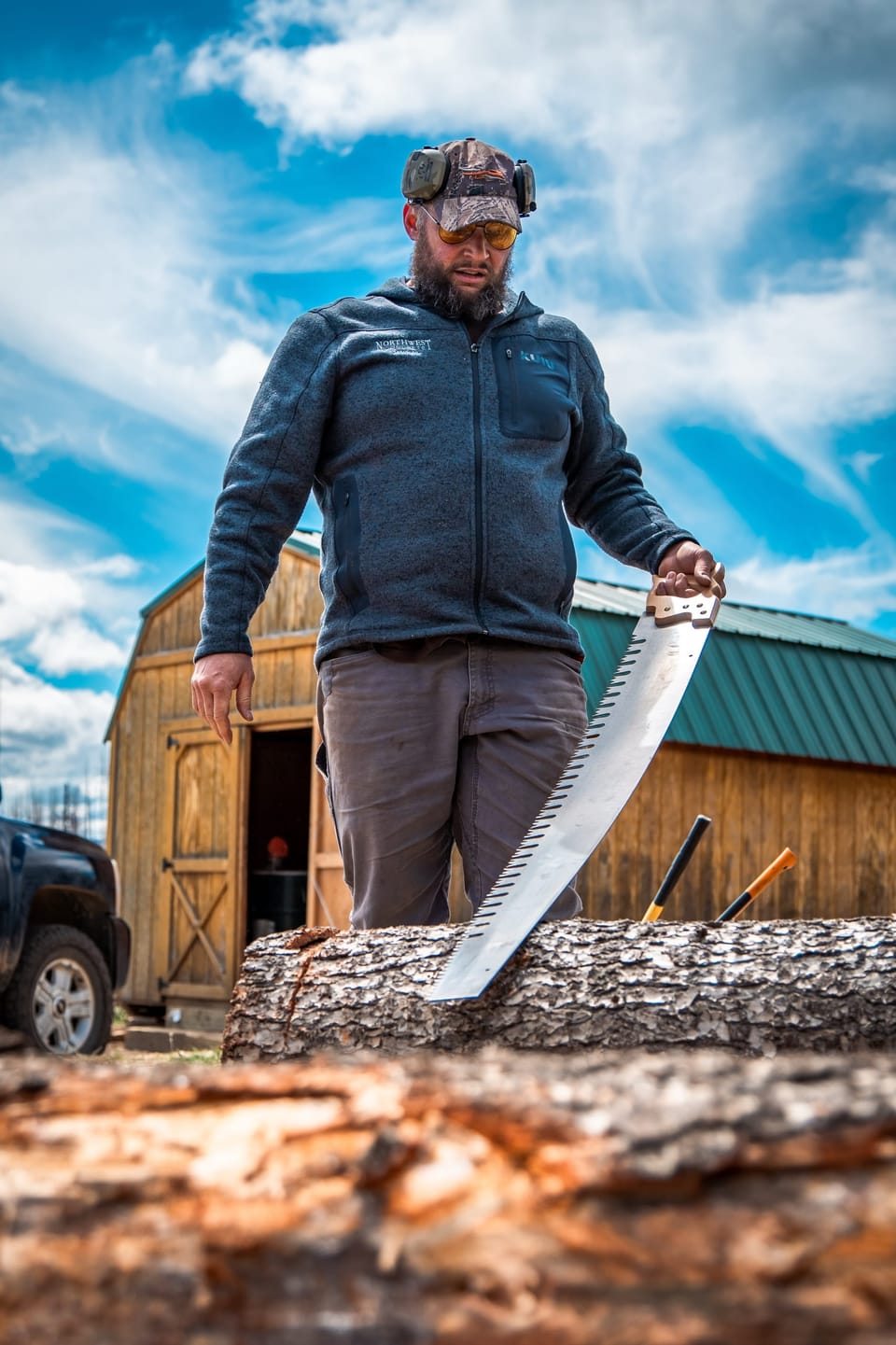 Man holding an axe beside a split log in the woods