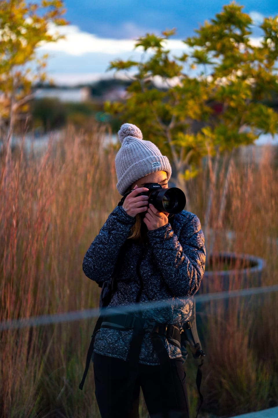 Woman with a camera among tall autumn grass