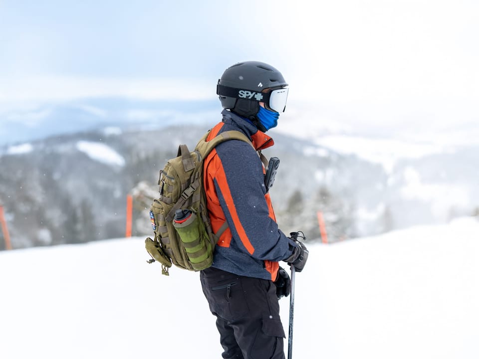 Skier with a backpack looking out over snowy mountains