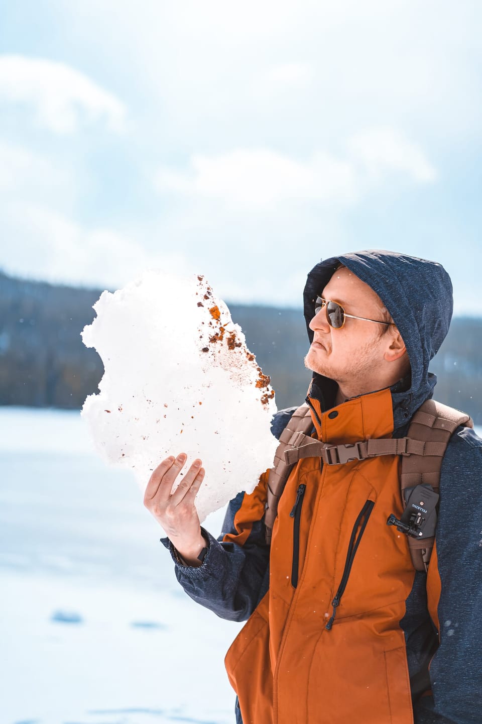 Woman in an orange jacket laughing in a bright snowy landscape
