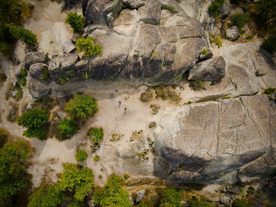 Top-down drone view of granite slabs and scattered green shrubs