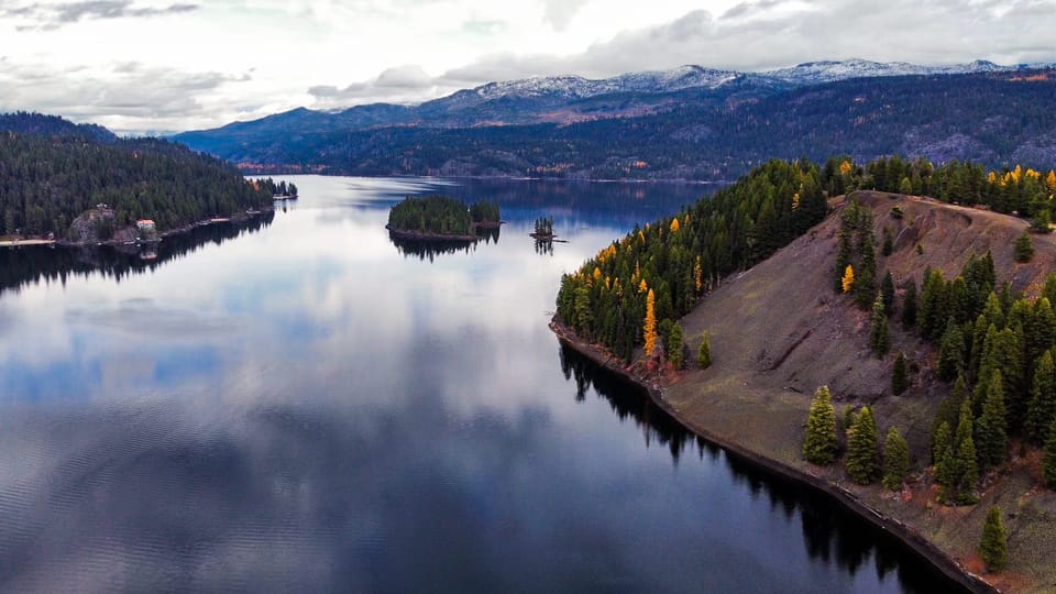 Aerial view of a calm lake reflecting forested hills