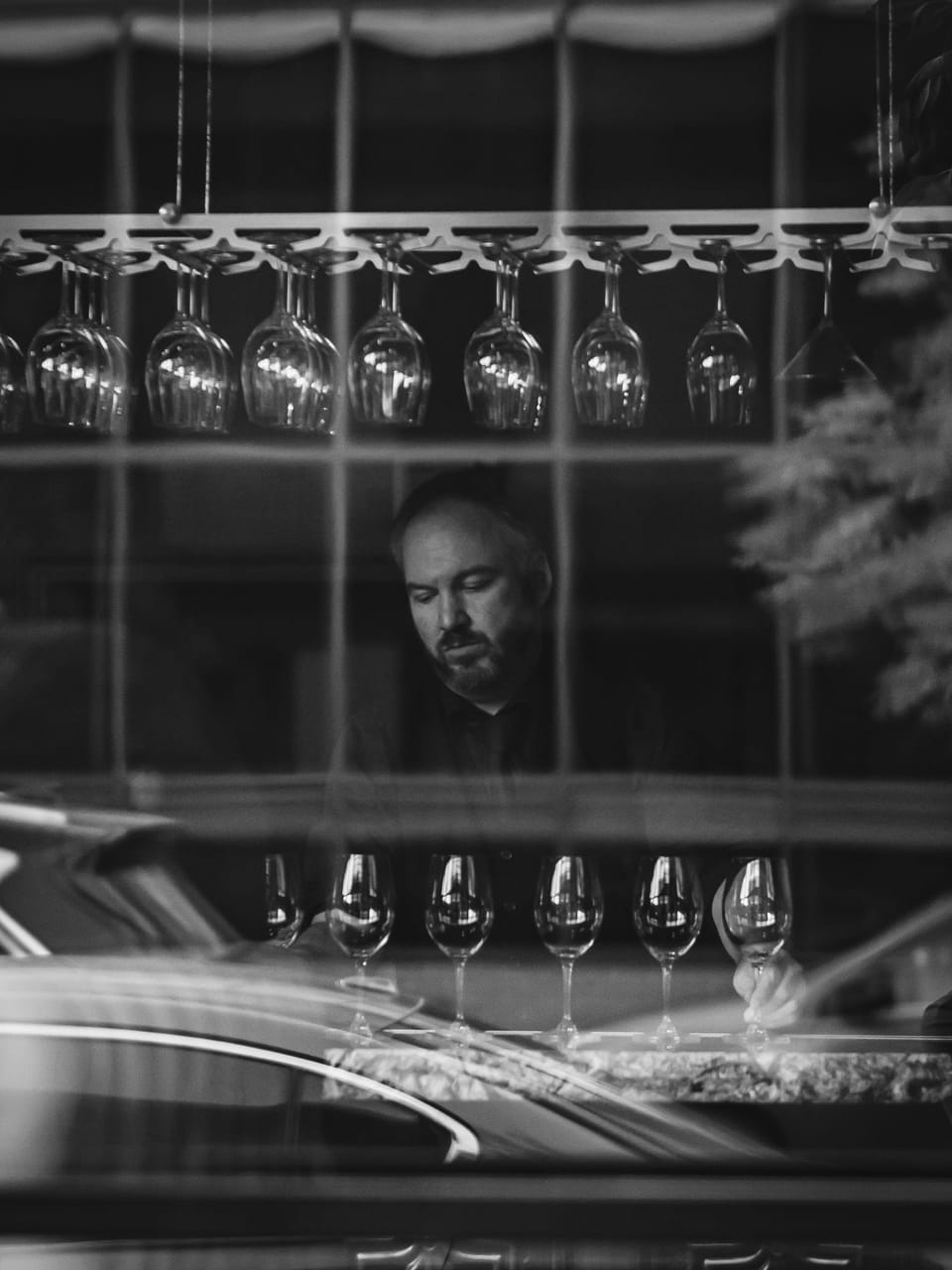 Black-and-white street scene of a man seen through a window