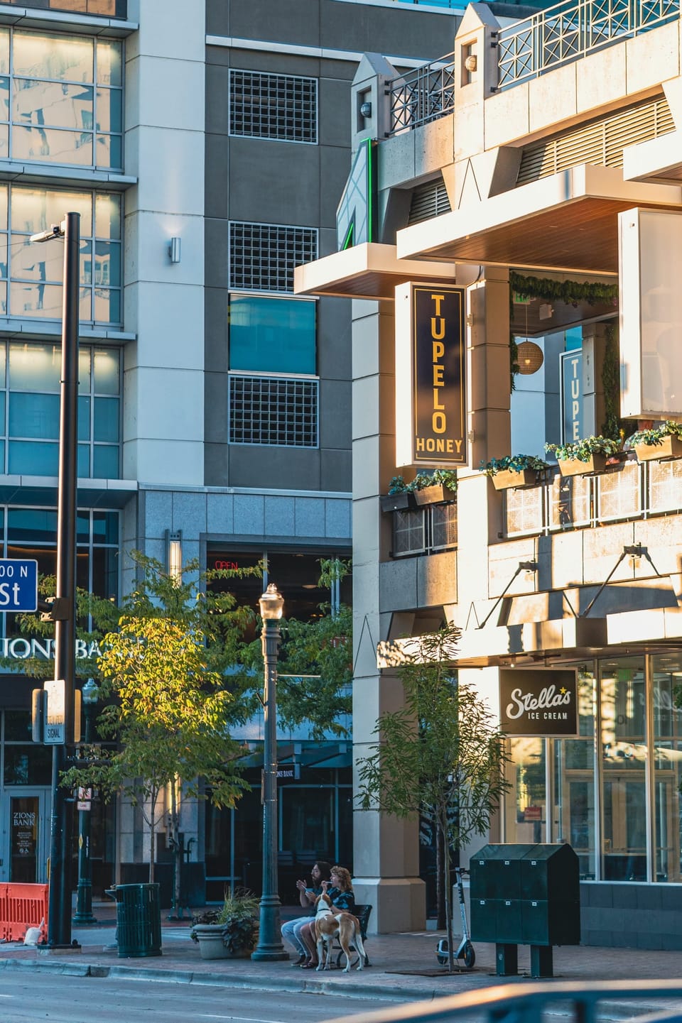 Downtown street corner with shops, trees and passing pedestrians