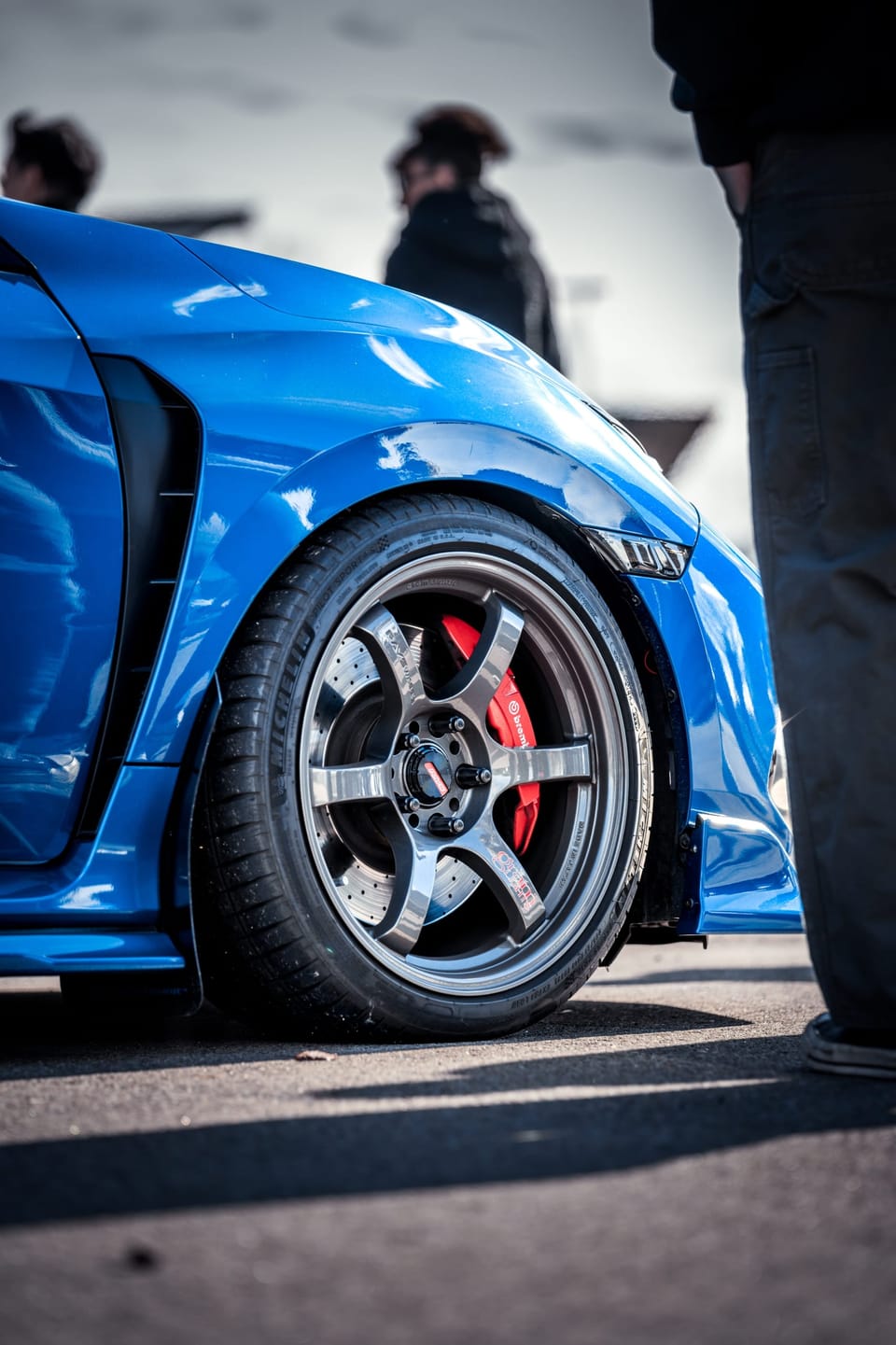 Bronze wheel on a blue sports car at a car meet