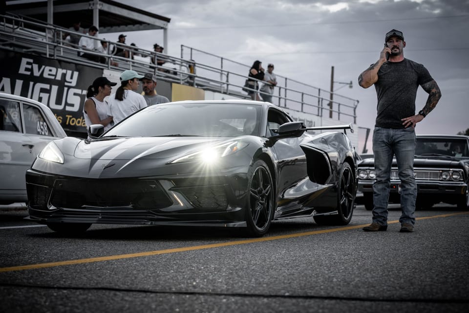 Man standing beside a silver mid-engine Corvette