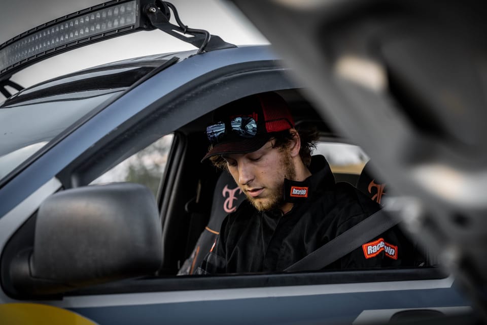 Driver in a cap looking out from a supercar's open door