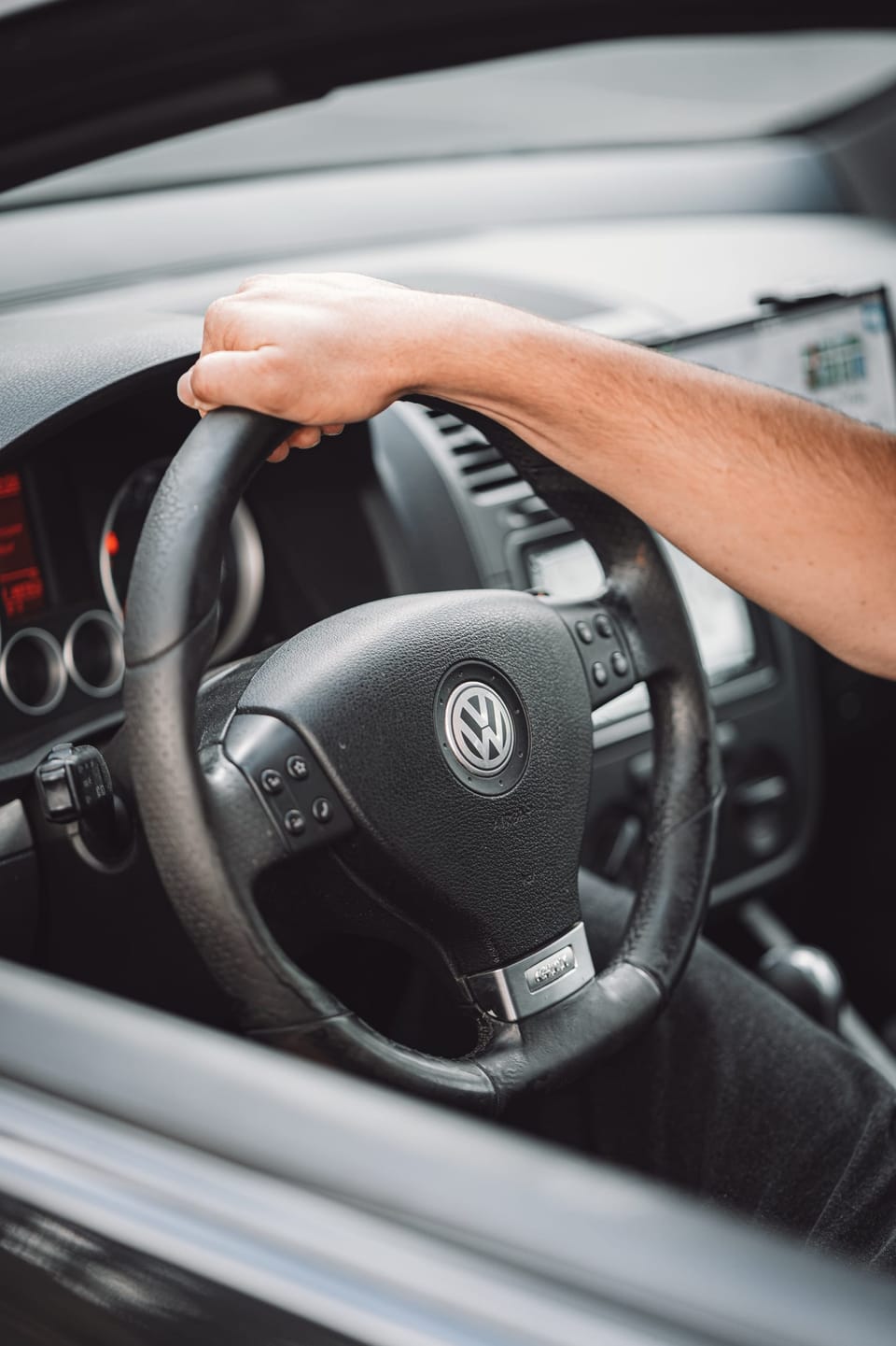 Driver's hand on the steering wheel of a hatchback