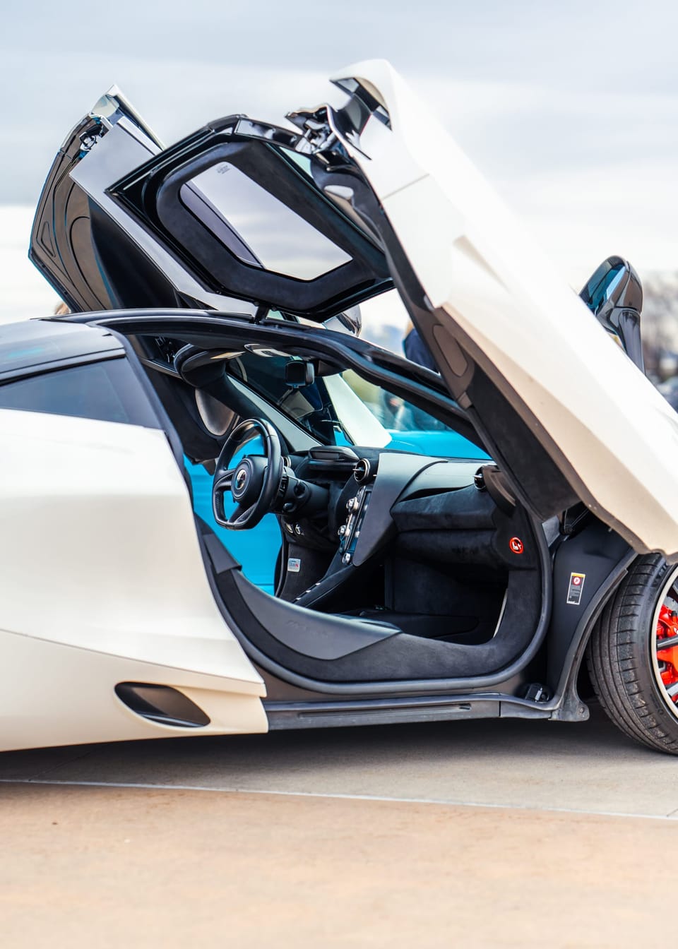 Open dihedral door of a white McLaren revealing the interior