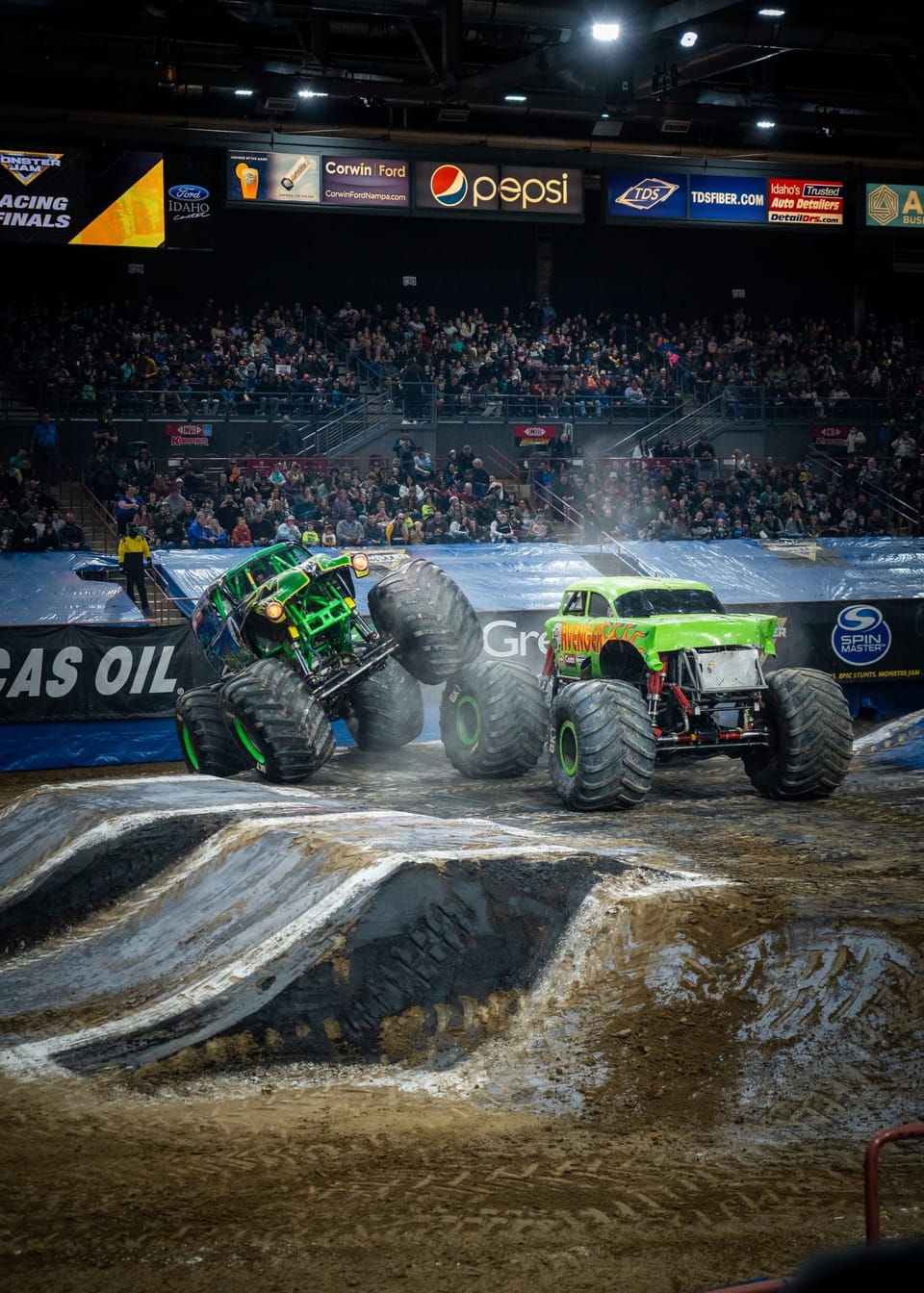 Green monster truck tearing through arena dirt