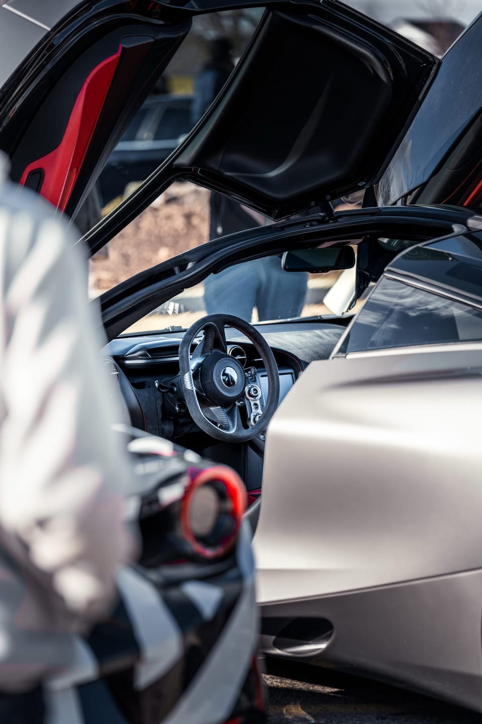 Silver supercar with its door open, reflections in the paint