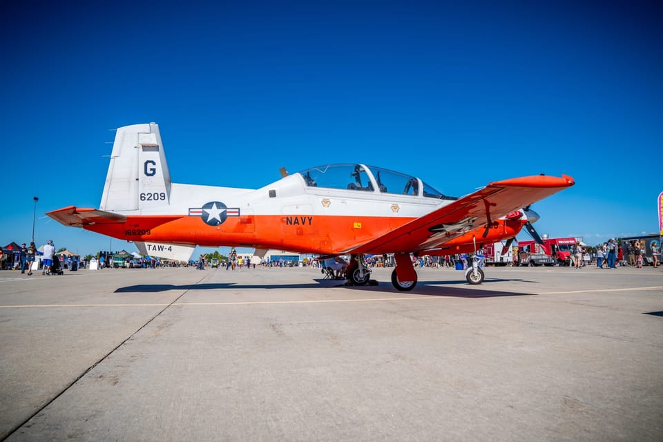 Red and white trainer aircraft on the tarmac under a blue sky