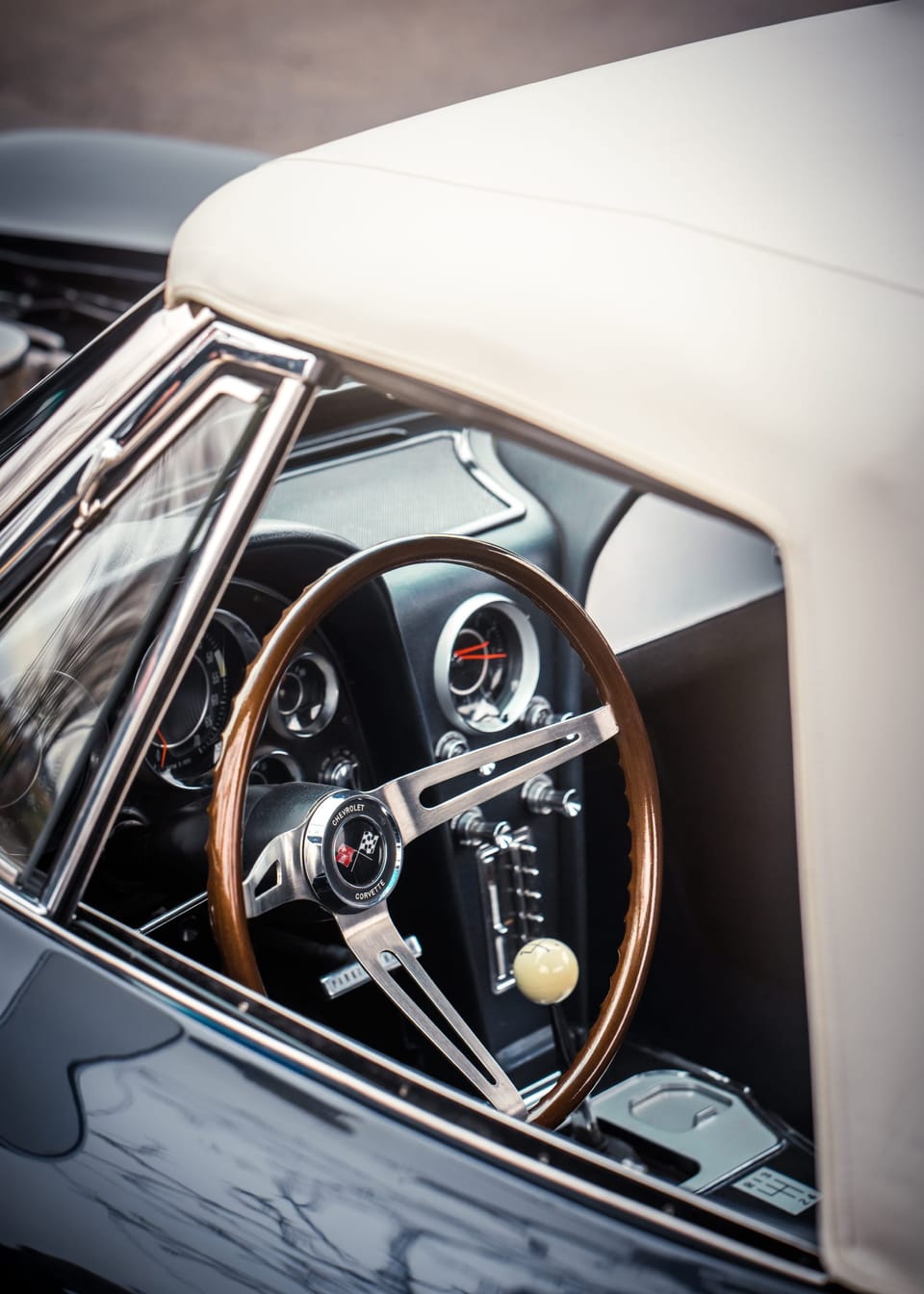 Classic car steering wheel seen past a white body