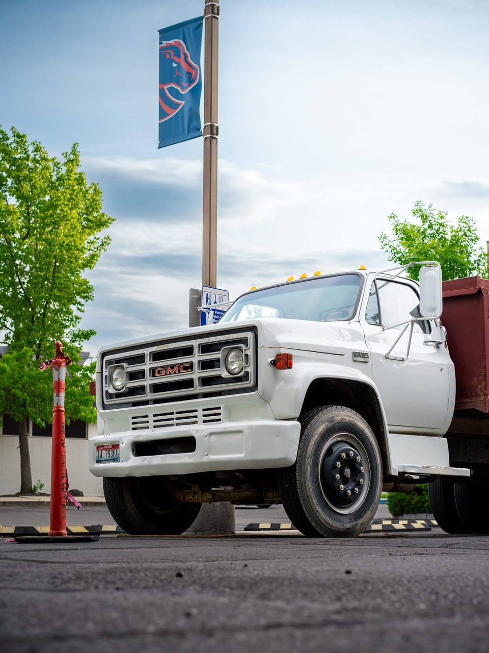 Vintage white pickup truck parked beside a flagpole
