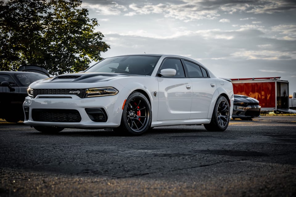 White Dodge Charger at a car meet under cloudy skies