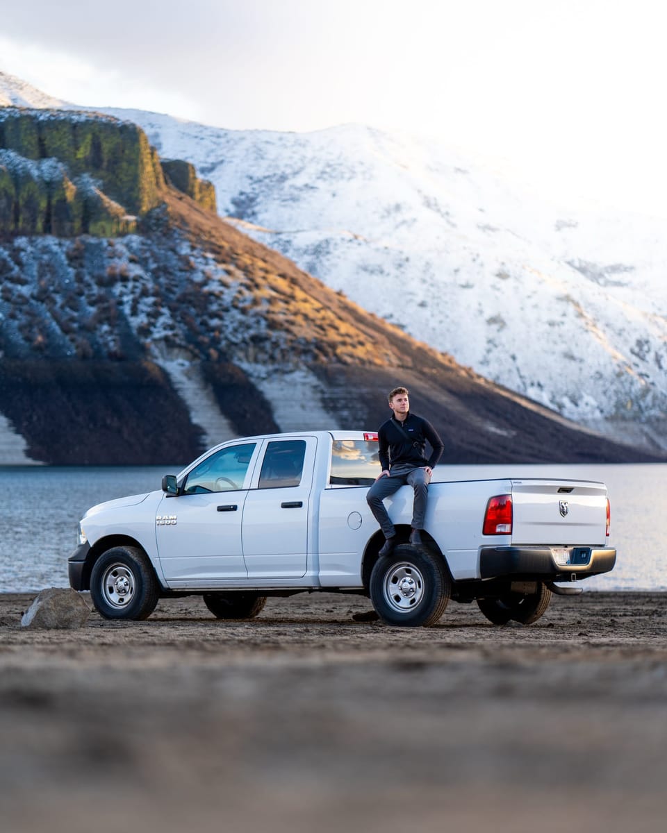White pickup truck parked below snowy mountains